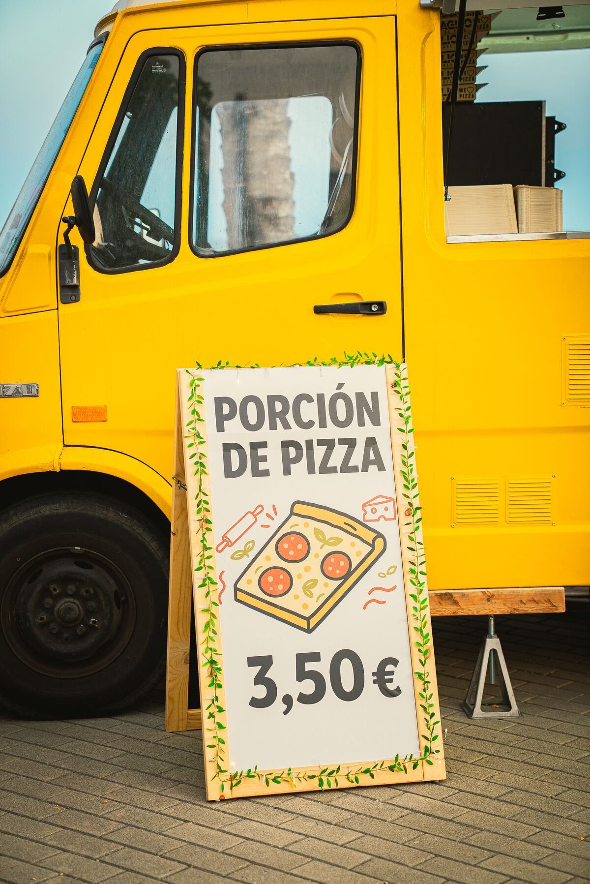 Cartel porción de pizza junto al food truck